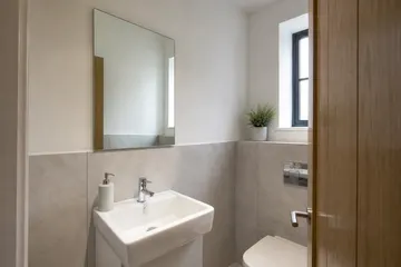 Plain bathroom mirror fitted in a small cloakroom